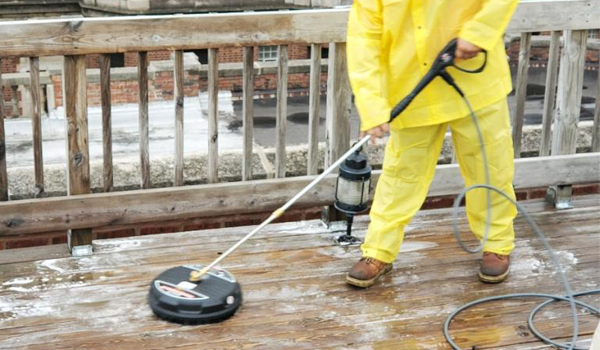 A man power washing a wooden deck
